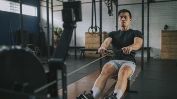 Homem remando em uma máquina de remo, focado na atividade física e no exercício. - Fitsse