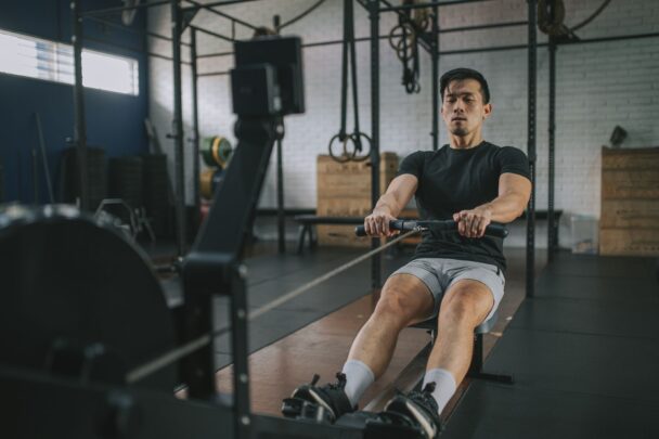 Homem remando em uma máquina de remo, focado na atividade física e no exercício. - Fitsse