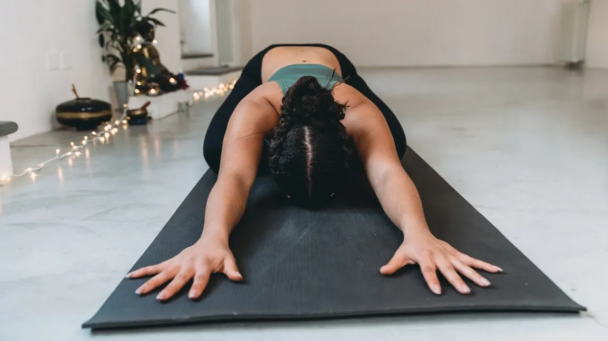 Uma mulher realizando uma pose de yoga em um tapete. - Fitsse