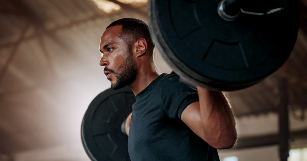 Homem levantando um haltere na academia, focado e determinado em seu treino de musculação. - Fitsse